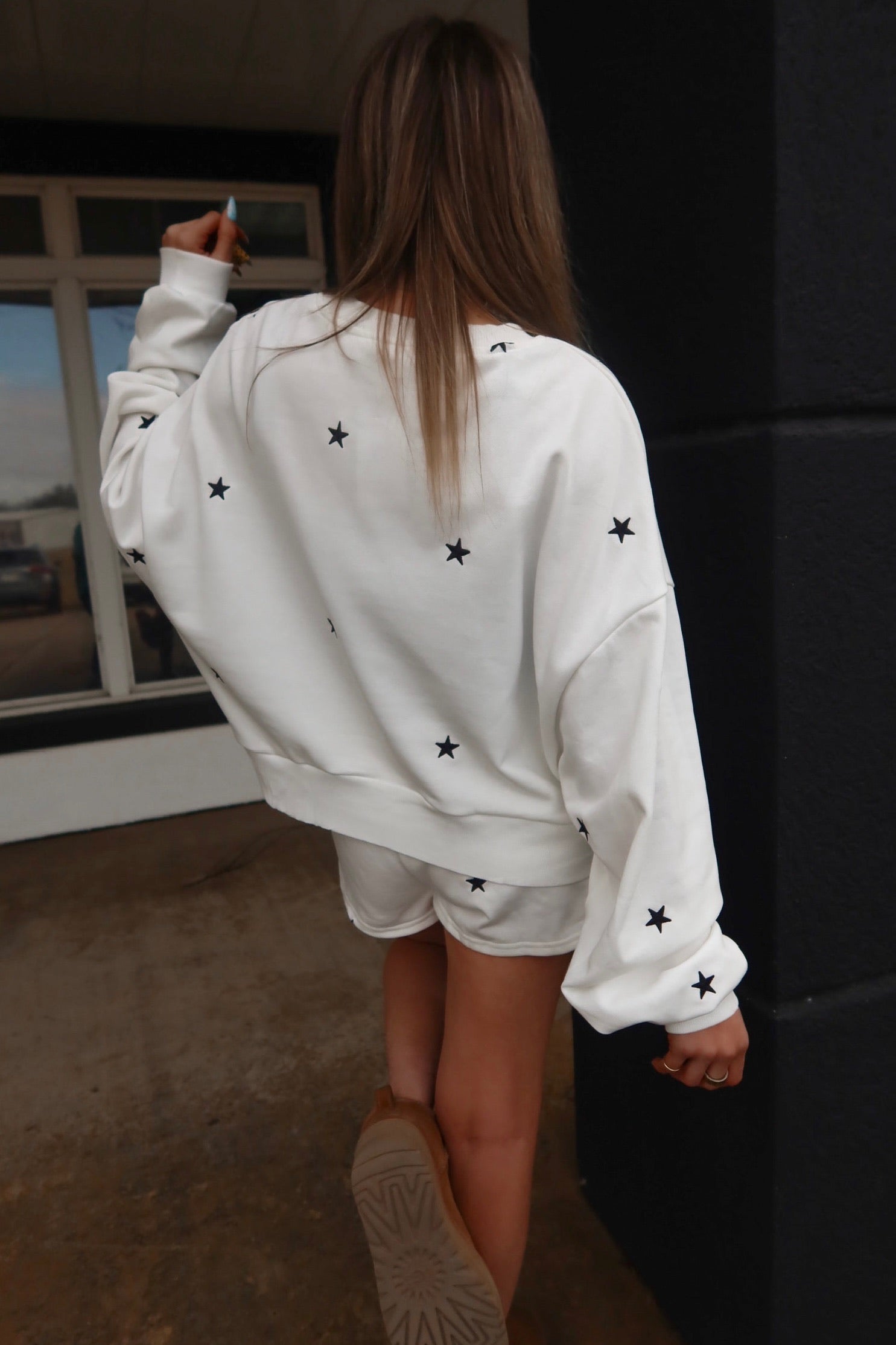 Person wearing a white sweatshirt with black star patterns indoors.
