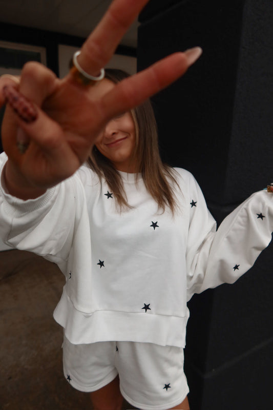 Person wearing a white outfit with black star patterns, partially covering their face.